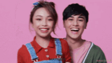 a man and a woman are smiling in front of a pink background that says malware on it