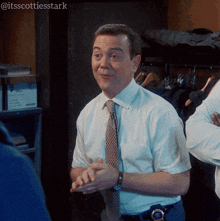 a man in a white shirt and tie stands in front of a closet with the hashtag itsscottiesstark on the bottom
