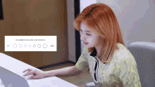 a woman with red hair is sitting at a desk with a laptop computer