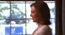 a woman stands in front of a window looking out