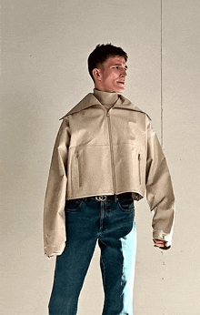 a man wearing a white jacket and blue jeans has a belt with a g on it