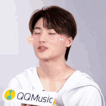 a young man with his eyes closed holds a sign that says qq music