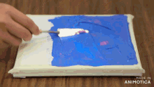 a person is using a spatula to spread blue paint on a canvas made in animatica