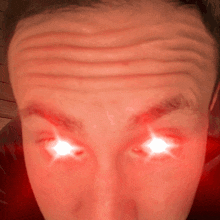 a close up of a man 's forehead with bright red eyes