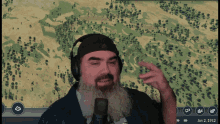 a man with a beard is wearing headphones and talking into a microphone in front of a screen that says jan 2 1912