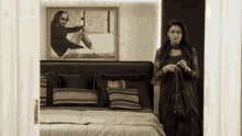 a woman stands in front of a bed with a picture of a man on it