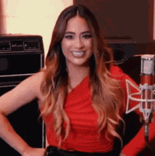 a woman in a red top is holding a microphone and smiling .