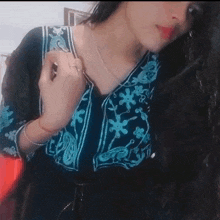 a woman wearing a black and blue top with a floral pattern