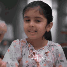 a little girl wearing a floral shirt with the words onehappyghan on the bottom