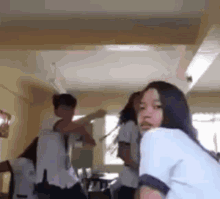 a group of students are dancing in a classroom while a girl looks on .