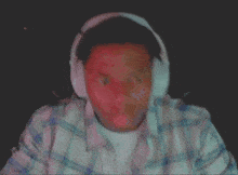 a man wearing headphones and a plaid shirt looks at the camera