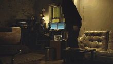 a man in a suit stands in front of two computer monitors in a living room