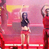 a woman in a crop top and shorts is dancing on a stage with two men