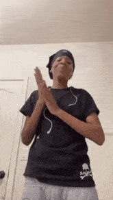 a woman wearing headphones and a black t-shirt is clapping her hands in a room .