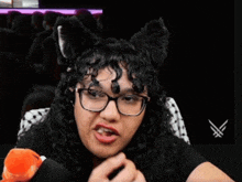 a woman wearing cat ears and glasses is sitting in front of a microphone