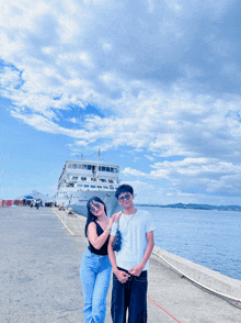 a man and a woman pose for a photo in front of a large ship