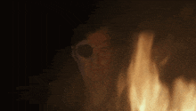 a man with a patch on his eye is standing in front of a fire ..