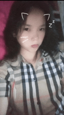 a girl wearing a plaid shirt has a cat ear sticker on her forehead