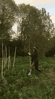 a woman is standing in a field holding a wand in her hand .