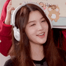 a woman wearing headphones is smiling and holding a card that says hearts