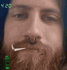 a man with a beard and a nose ring smoking a cigarette with the time 4:20