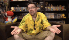 a man in a yellow shirt is sitting in front of a bookshelf