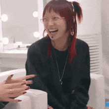 a woman with red hair and glasses is sitting in a chair laughing