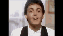 a close up of a man in a tuxedo and bow tie singing .