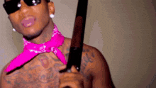 a shirtless man wearing a pink bandana and sunglasses holds a knife