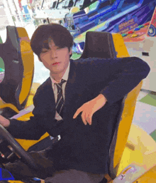 a man in a suit and tie is sitting in a yellow car in an arcade .