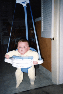 a baby in a fisher price swing is looking at the camera