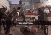 a group of people are standing around a man laying on the ground in front of a red and white van