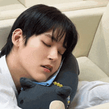 a young man sleeping on a couch with a stuffed animal in his lap