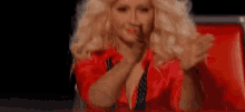 a blonde woman in a red jacket is sitting in a red chair .