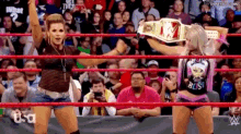 a woman is holding a wrestling championship belt in a ring .