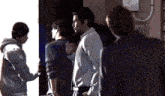 a group of men are standing in a dark room talking to each other .