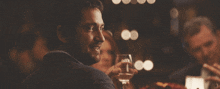 a man in a suit is holding a glass of wine in his hand