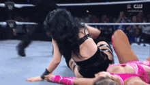 two women are wrestling in a ring with a cw logo on the bottom