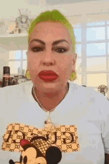 a woman with green hair and red lips is wearing a white t-shirt with a mickey mouse on it .