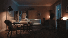 a woman sits in a chair in a living room with a couch