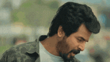 a man with a beard is wearing a camouflage jacket and a white shirt