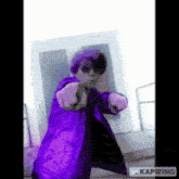 a person in a purple jacket is pointing at the camera .