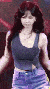 a woman in a blue tank top and blue shorts is dancing on a stage .