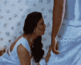 a woman is kissing a man 's leg in front of a wall with flowers on it .