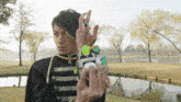 a man in a black and gold uniform is holding a green and white toy