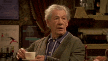 an older man is holding a cup of coffee in front of a poster that says ' sherlock '