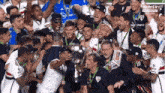 a group of soccer players are celebrating with a trophy in their hands .