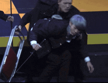 a man in a black jacket with a skull on it is carrying another man on his back