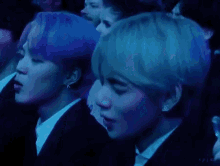 a couple of men are sitting next to each other in a dark room with a blue light behind them .