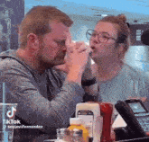 a man and a woman are sitting at a table with ketchup and mustard bottles